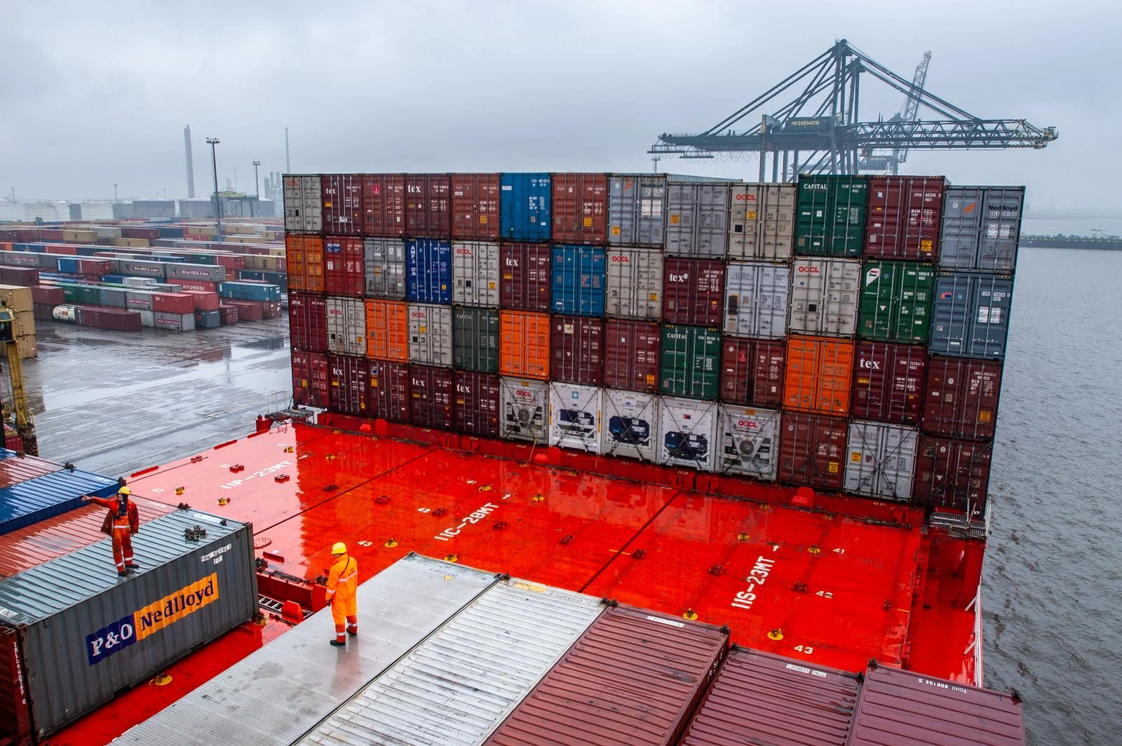 Dockworkers and shipping containers on a red ship deck